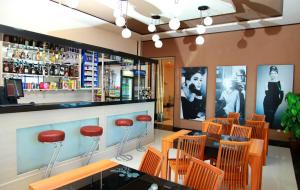un restaurante con bar con taburetes rojos en Zarafshan Grand Hotel FIEZ, en Malik