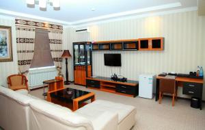 Una sala de estar con un sofá blanco y un televisor. en Zarafshan Grand Hotel FIEZ, en Malik