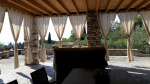 een paviljoen met witte gordijnen en een bank op een patio bij Casa Quarole Garda-Meer in Cavaion Veronese
