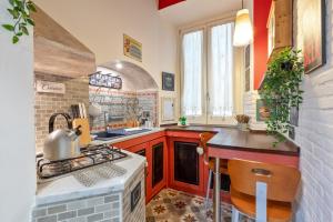 La cuisine est équipée de placards rouges et d'un four avec plaques de cuisson. dans l'établissement Rome as you feel - Casa Governo Vecchio, à Rome