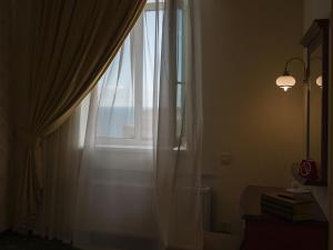 a window with white curtains and a lamp and books at ArcadiaSky in Odesa