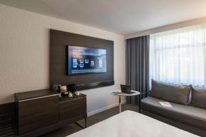 a hotel room with a couch and a tv at Novotel Lyon Bron in Bron
