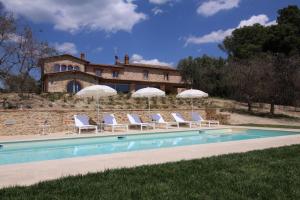 una piscina con sillas y sombrillas frente a un edificio en Mulino della Solaia - Arceno Rentals Club, en Monticiano