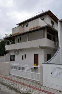 una casa blanca con una valla delante en Apartamentos Bombinhas - 140 metros da Praia, en Bombinhas