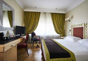 Habitación de hotel con cama, escritorio y TV. en FH55 Grand Hotel Palatino, en Roma