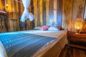 a bed in a room with a wooden wall at Lost and Found in Koh Rong Sanloem