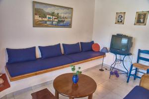 a living room with a blue couch and a tv at Almyriki in Methana