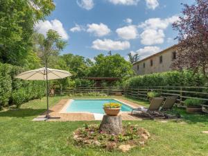 a pool with an umbrella and two chairs and a table at Casina di Teo by VacaVilla in Monteriggioni