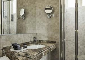 
a bathroom with a sink, mirror, and bathtub at FH55 Grand Hotel Palatino in Rome
