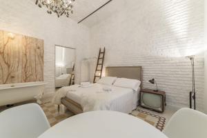 een witte slaapkamer met een bed en een televisie bij Romantic Vintage Colosseum Suite in Rome