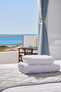 a stack of towels on a bed with a view of the ocean at Muses Rooms Milos in Provatas
