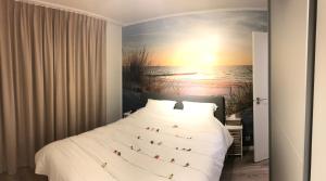 een slaapkamer met een bed en een schilderij van de oceaan bij Castel aan zee in Koksijde