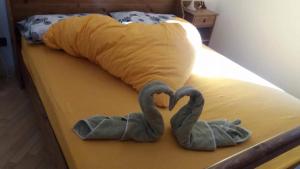 2 cygnes de serviettes assises au-dessus d'un lit dans l'établissement Max 's Siusi Apartement, à Alpe di Siusi