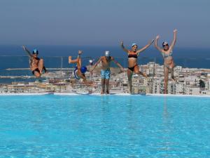 a group of people jumping into the water at a swimming pool at Villa Coppitella, rooms & apartments in Vieste