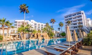 a swimming pool with chaise lounge chairs and umbrellas at Adams Beach Hotel & Spa in Ayia Napa