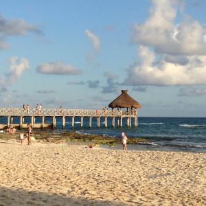 a group of people on the beach near a pier at Suites at Mayan Palace Vidanta Resort Riviera Maya in Playa del Carmen
