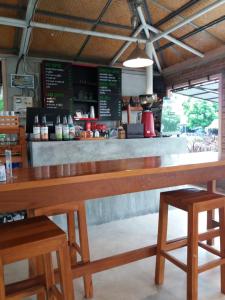 a large wooden counter in a restaurant with two benches at Raina-Suanpa Lung Sood Farmstay in Ban Mot Deng