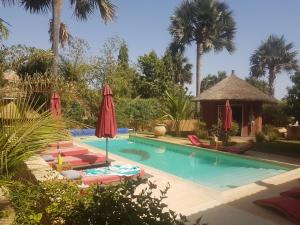 einen Pool mit Stühlen und einem Pavillon in der Unterkunft Keur Palmier Saly in Saly Portudal