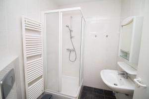 a white bathroom with a shower and a sink at Hello Zeeland - Appartement Port Scaldis 13-111 in Breskens
