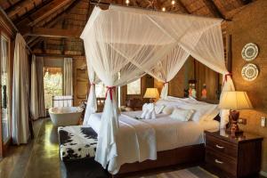 a bedroom with a canopy bed and a bath tub at Jabulani Safari in Kapama Private Game Reserve