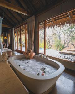 a woman laying in a bath tub in a room at Jabulani Safari in Kapama Private Game Reserve