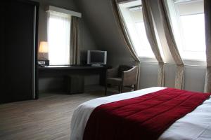 a bedroom with a bed and a desk and windows at Biznis Hotel in Lokeren