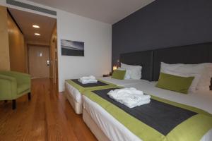 a hotel room with two beds and a green chair at ARTS IN Hotel Conde Carvalhal in Funchal