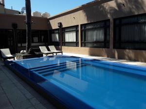ein blauer Swimmingpool mit zwei Stühlen neben einem Gebäude in der Unterkunft Cristobal Hotel Boutique in Concordia