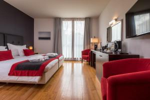 a hotel room with a bed and two red chairs at ARTS IN Hotel Conde Carvalhal in Funchal