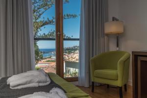 a bedroom with a bed and a chair and a window at ARTS IN Hotel Conde Carvalhal in Funchal