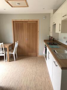 kuchnia z drewnianymi drzwiami i stołem w obiekcie Coastal Retreat w mieście Lowestoft
