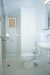 a white bathroom with a toilet and a sink at Garifalo Apartments in Kalyves