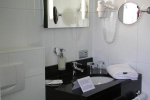 a bathroom with a sink and a phone at Biznis Hotel in Lokeren