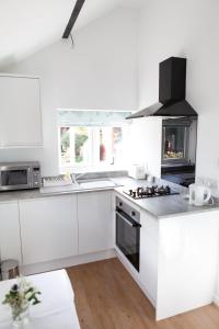 een keuken met witte kasten en een fornuis met oven bij Elm Cottage Touring Park in Whitegate