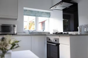 uma cozinha com armários brancos, um lavatório e um micro-ondas em Elm Cottage Touring Park em Whitegate