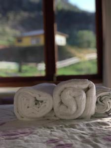 a pile of towels on a bed with a window at Casa Cambuí Hospedagem Rural in Rio Prêto