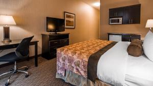 a hotel room with a bed and a desk and a television at Best Western Plus Estevan Inn & Suites in Estevan
