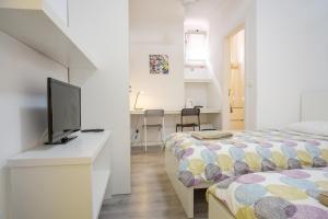 1 dormitorio con 2 camas y escritorio con TV en Tagus 5 Colours Suites, en Algés