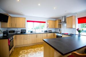 a kitchen with wooden cabinets and a black counter top at ROUND PARK- Private and spacious family bungalow with parking in Laugharne