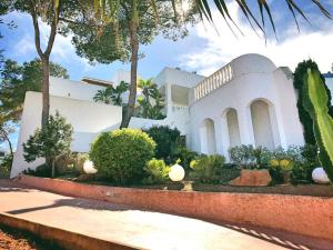 une maison blanche avec des arbres et des plantes devant elle dans l'établissement DOS MONOS, à Bahía de Sant Antoni