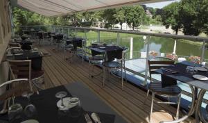 a balcony of a restaurant with tables and chairs at Logis Hôtel Auberge de L'Etang in Magnac-Bourg