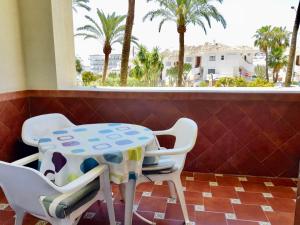 a table and chairs in a balcony with palm trees at G&G Benalbeach Sea Views in Benalmádena