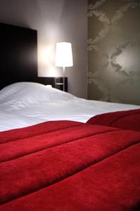 a bedroom with a bed with a red blanket at Biznis Hotel in Lokeren