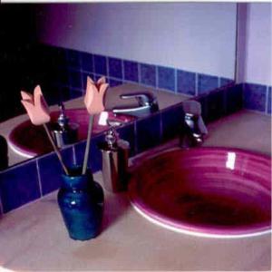 a bathroom with a red sink with a vase with flowers at Posada Tresmentiras in Aldeanueva del Camino