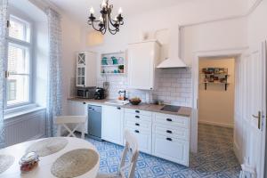 a kitchen with white cabinets and a table and chairs at Hibay Apartman in Eger