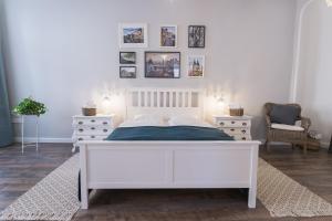 a bedroom with a white bed and two dressers at Hibay Apartman in Eger