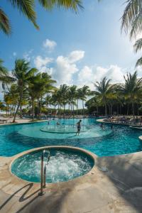 a swimming pool with palm trees and people in it at Hacienda Tres Rios Resort Spa & Nature Park - All Inclusive in Playa del Carmen