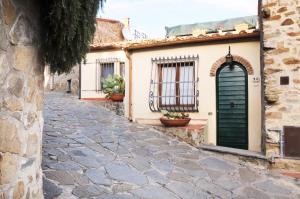 a cobblestone street with a green door and buildings at Appartamento San Simone in Castiglione della Pescaia