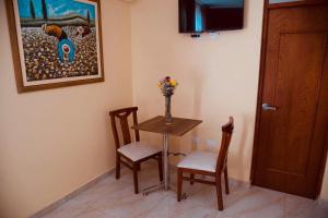una habitación con una mesa y dos sillas y un jarrón con flores en Hotel Central, en Trujillo