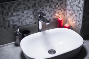 lavabo blanco en el baño con 2 velas en Victory Apartment, en Zhensna Polʼska